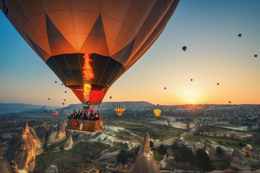 Kosz balonu z pasażerami nad Kapadocją o wschodzie słońca