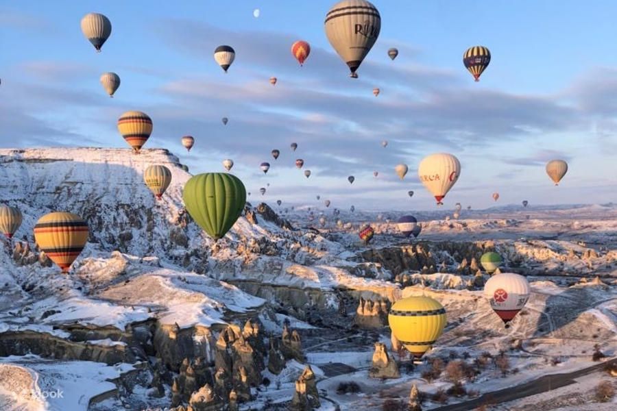 Balony na ogrzane powietrze nad skalnymi kominami Göreme o wschodzie słońca