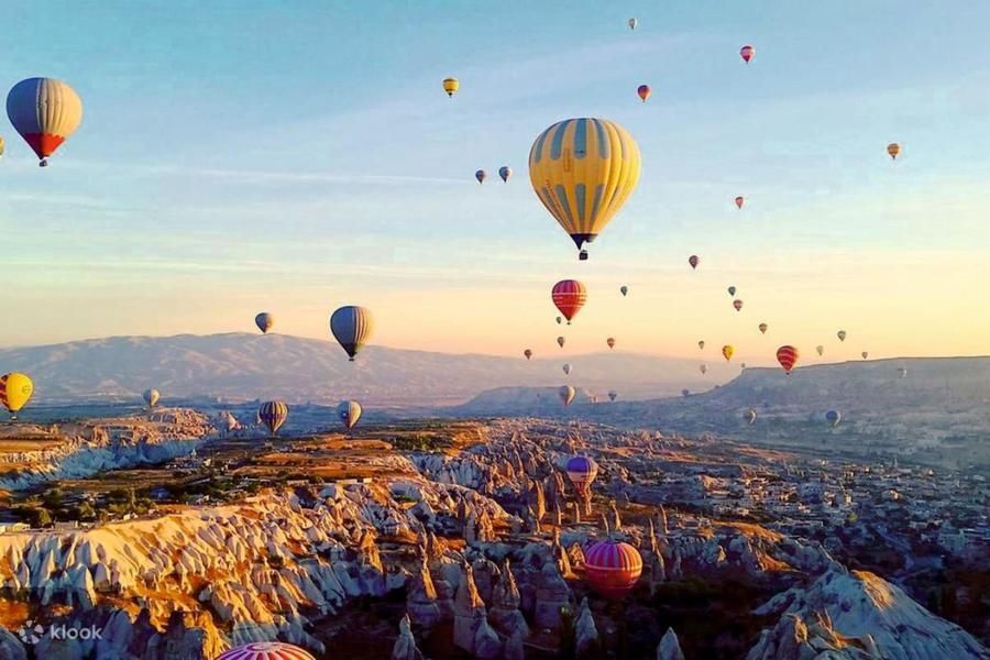Balon na ogrzane powietrze unoszący się nad doliną w Kapadocji o świcie