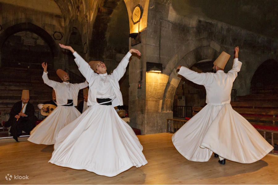 Wirujący derwisze w białych szatach podczas ceremonii Sema w karawanseraju