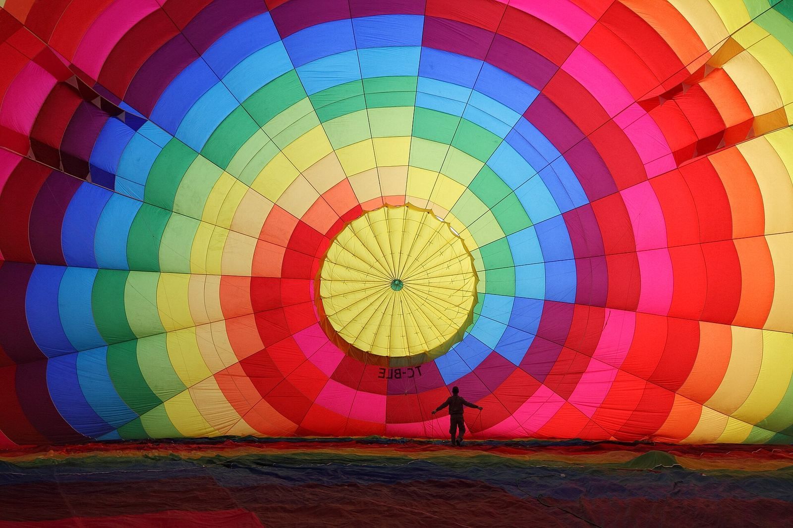 Napełnianie powłoki balonu zimnym powietrzem przed startem, obok ekipa naziemna